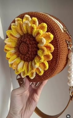 a hand holding a purse with a sunflower on the front and side of it