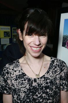 a woman standing in front of a poster with flowers on it's face and smiling