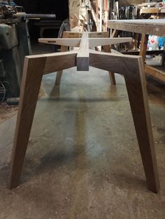 a wooden table sitting in a room next to a pile of wood