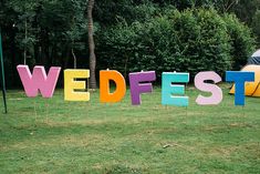 the word wedest spelled out in large letters on top of green grass with trees in the background