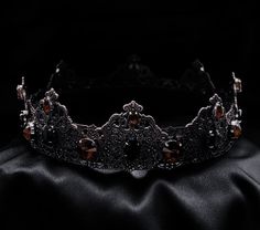 a tiara with red stones on it sitting on a black cloth