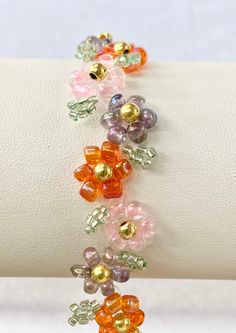 multicolored glass beaded bracelet on a white wristband with gold and silver beads