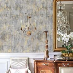 a room with a chair, mirror and chandelier on the side table in front of it