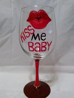 a wine glass with the words kiss me baby painted on it and a red lip