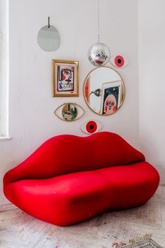 a large red couch sitting in front of a mirror on the side of a wall