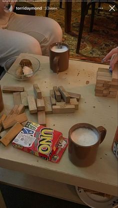 two people are sitting at a table with blocks and marshmallows on it