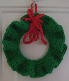 a crocheted christmas wreath hanging on a door handle with a red and green ribbon