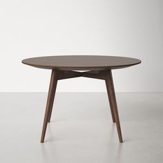 an oval table with wooden legs and a circular top, on a white floor in front of