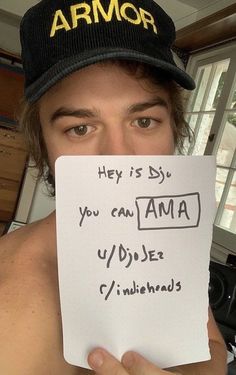 a man holding up a piece of paper with writing on it in front of his face