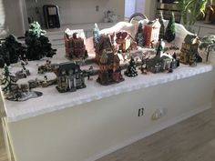 a table topped with lots of small christmas village figurines on top of a counter