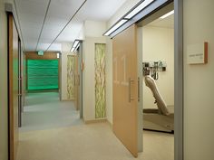 an empty hospital hallway with medical equipment on the wall and doors leading to another room