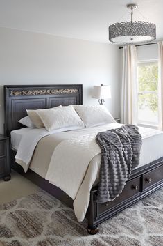 a bedroom with a large bed and a chandelier hanging from it's ceiling