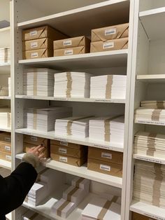 a woman is looking at boxes on shelves in a storage room with white shelving