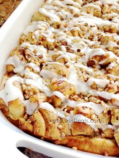 a casserole dish filled with cinnamon rolls covered in icing and toppings