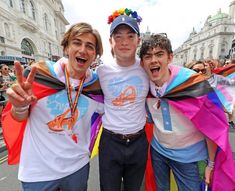 three young men standing next to each other in the street