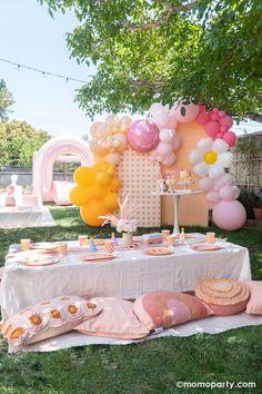 a table set up with balloons, cake and desserts on it in the grass