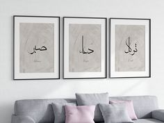 three framed pictures hang on the wall above a couch in a living room with pink pillows