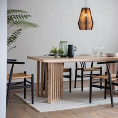 a wooden table with chairs around it and a plant in the corner next to it