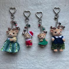 three key chains with small stuffed animals hanging from it's sides and wearing christmas outfits