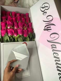 a person is opening a box with pink roses in it