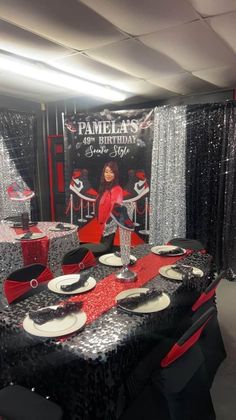 a table set up with black and red decorations