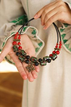 a woman wearing a red and black beaded bracelet with an ornate cross on it