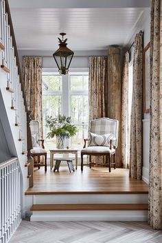 a living room filled with furniture next to a window covered in curtains and drapes