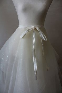 a white dress with a bow on the waist and sequins on the skirt