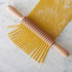 a yellow comb with wooden handles on a marble counter top next to a bag of flour