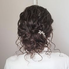 the back of a woman's head with curly hair and flowers in her hair