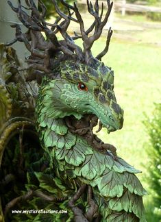 a green dragon statue sitting on top of a lush green field