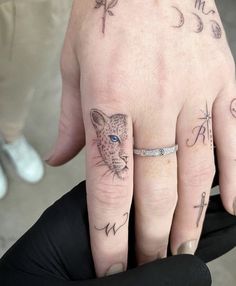 two people with tattoos on their fingers and one has a leopard, arrow, and cross