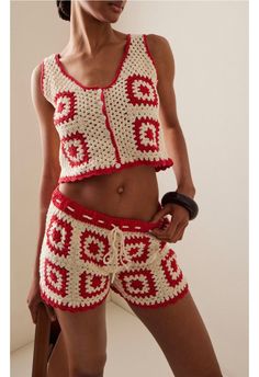 a woman in red and white crocheted clothing posing for the camera with her hand on her hip