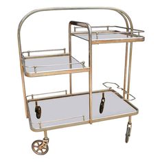 a three - tiered metal trolley with wheels is shown against a white background the cart has two glass shelves on each side