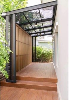 an open porch with wooden steps and metal railings, surrounded by greenery on both sides