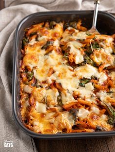 a casserole dish with spinach, cheese and sauce in it on a wooden table