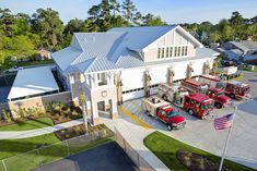 several fire trucks parked in front of a white building with an american flag on the roof