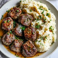 a white plate topped with mashed potatoes and meatballs