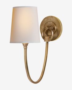 a wall light with a white shade on the side and a gold finish to it