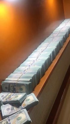 stacks of money sitting on top of a wooden counter next to a wall with lights