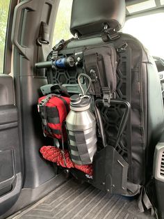 the back end of a vehicle with various items in the cargo area, including a backpack and water bottle