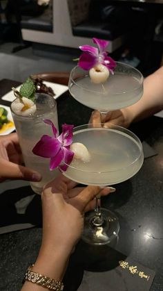 two people are holding glasses with drinks in them and flowers on the rims,