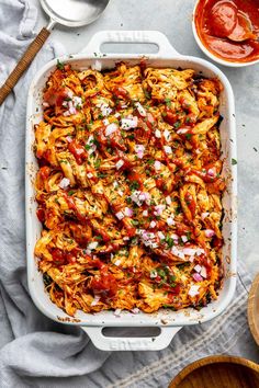 a casserole dish filled with pasta, sauces and onions on a table