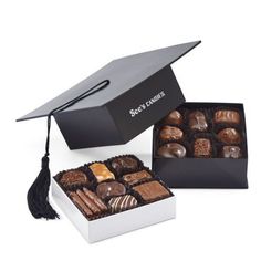 a graduation cap sitting on top of a box filled with chocolates