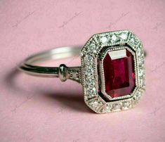 an engagement ring with a red stone surrounded by diamonds