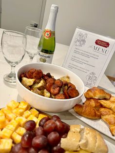 a table topped with lots of different types of food next to wine bottles and glasses