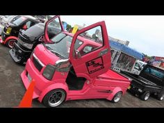 several cars are parked in a parking lot with their doors open and one is pink