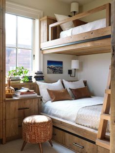 a bedroom with bunk beds and drawers in the corner next to a window that has a plant on it