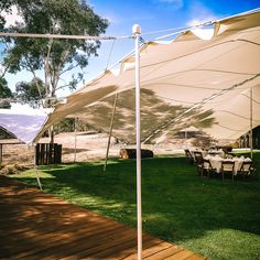 a large white tent sitting on top of a lush green field next to a wooden deck