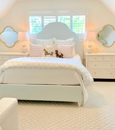 a bedroom with white furniture and pink pillows on the bed, along with two small stuffed animals